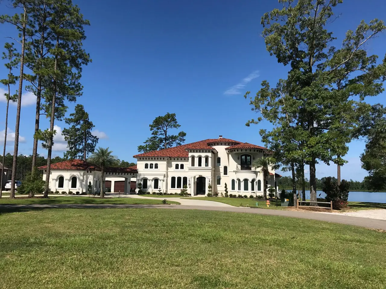 White Mediterranean-style stucco home with a red tile roof beside a lake