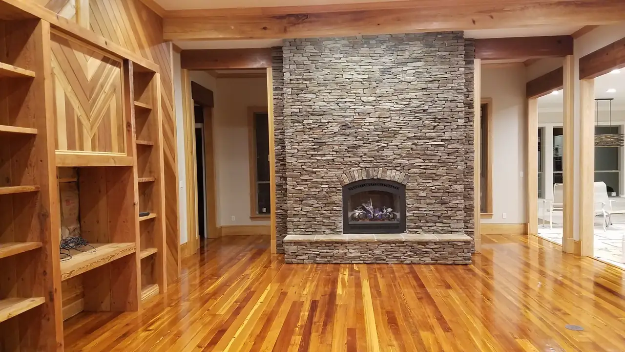 Floor-to-ceiling stacked stone fireplace in a living room with wood floors