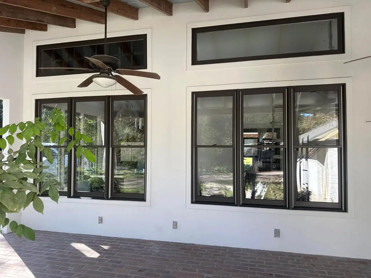 Smooth white stucco on a covered porch with black-framed windows and a brick floor